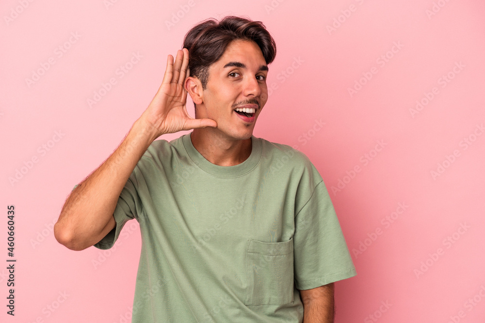 Young mixed race man isolated on white background trying to listening a gossip. Young mixed race man isolated on white background trying to listening a gossip.