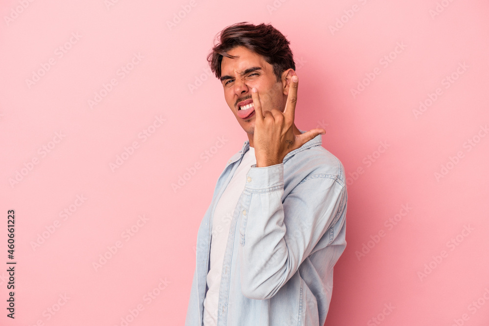 Young mixed race man isolated on white background showing rock gesture with fingers Young mixed race man isolated on white background showing rock gesture with fingers