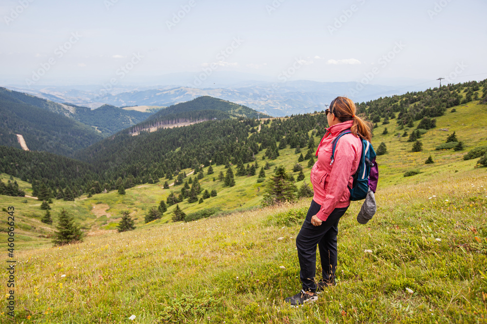 Woman hiker on top , amazing view of green valley and forest