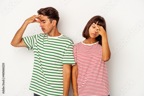 Young mixed race couple isolated on white background having a head ache, touching front of the face.