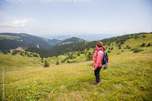 Woman hiker on top , amazing view of green valley and forest