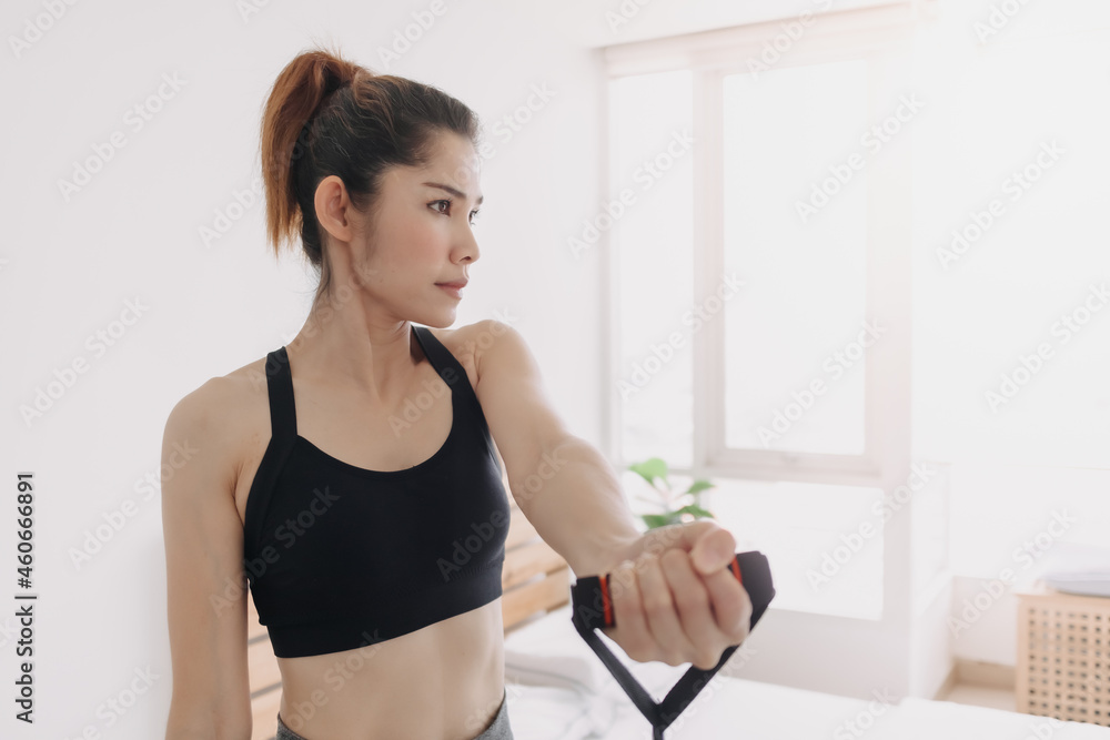 Asian woman does Resistance Bad Cross Body Upper Chest Fly workout in her room.