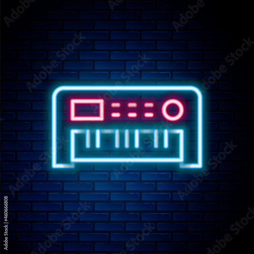 Glowing neon line Music synthesizer icon isolated on brick wall background. Electronic piano. Colorful outline concept. Vector