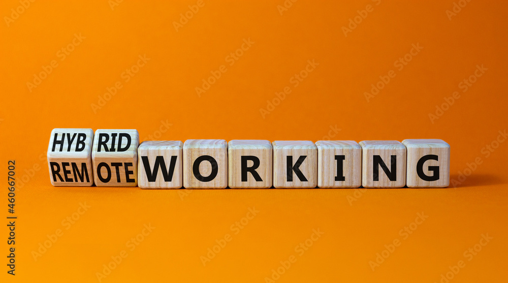 Hybrid or remote working symbol. Turned wooden cubes and changed words 'remote working' to 'hybrid working'. Beautiful orange background. Business, hybrid or remote working concept, copy space. Hybrid or remote working symbol. Turned wooden cubes and changed words 'remote working' to 'hybrid working'. Beautiful orange background. Business, hybrid or remote working concept, copy space.