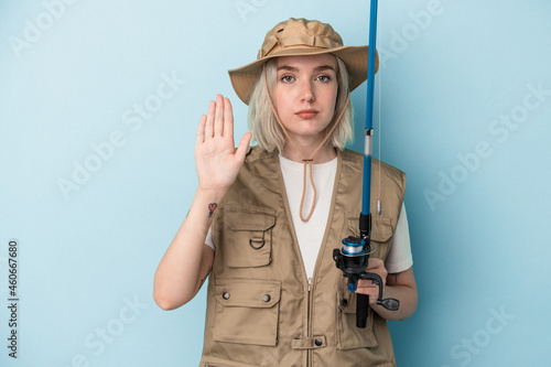 Young caucasian fisherwoman holding a rod isolated on blue background standing with outstretched hand showing stop sign, preventing you.