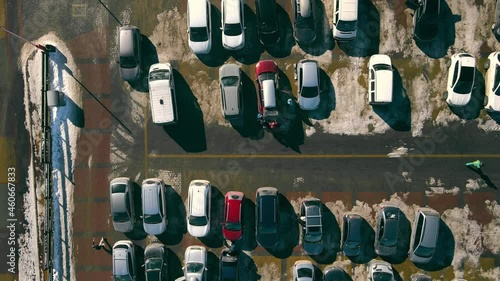 Aerial view on top car parking in winter. Snow melting around cars in the parking lot.