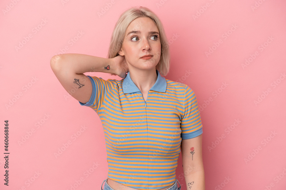Young caucasian woman isolated on pink background touching back of head, thinking and making a choice. Young caucasian woman isolated on pink background touching back of head, thinking and making a choice.