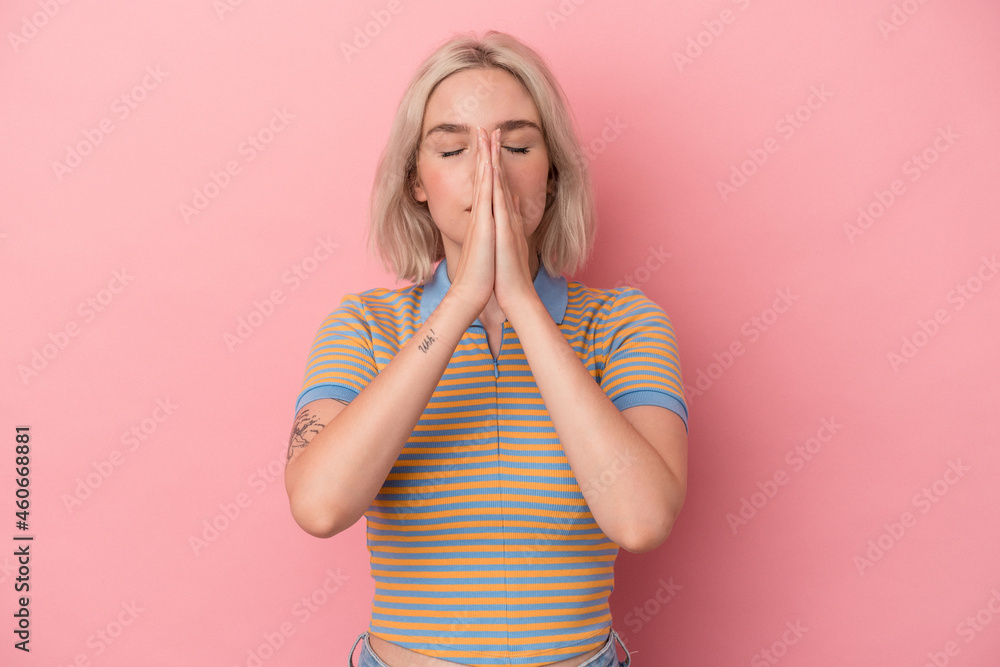 Young caucasian woman isolated on pink background holding hands in pray near mouth, feels confident. Young caucasian woman isolated on pink background holding hands in pray near mouth, feels confident.