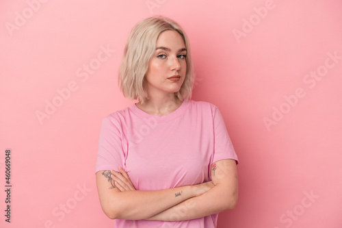 Young caucasian woman isolated on pink background suspicious, uncertain, examining you.