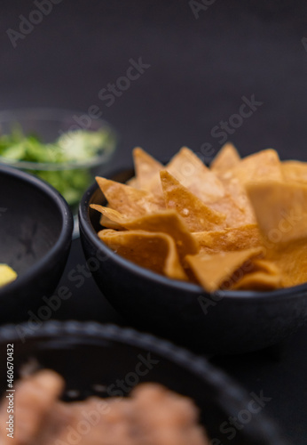 Bowls of tortilla chips and refried beans with black background
