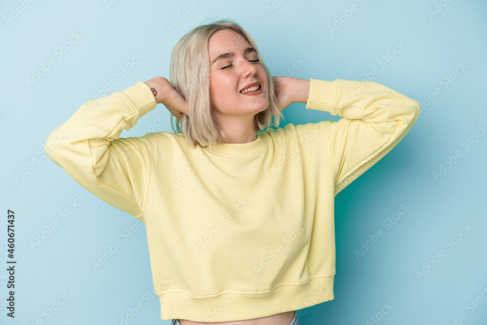 Young caucasian woman isolated on blue background feeling confident, with hands behind the head. Young caucasian woman isolated on blue background feeling confident, with hands behind the head.