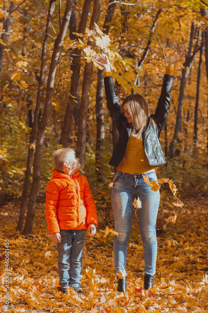 Single parent family playing with autumn leaves in park. Happy mom and son throw autumn leaves up in fall park. Single parent family playing with autumn leaves in park. Happy mom and son throw autumn leaves up in fall park.