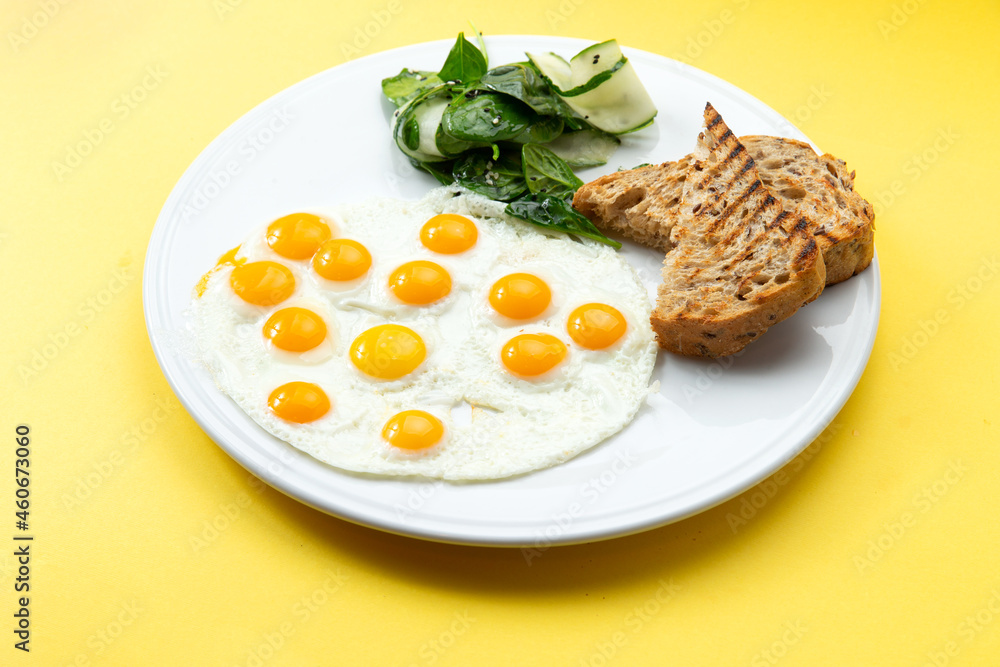 Fried eggs from quail eggs and toast in a plate. on a yellow background. Fried eggs from quail eggs and toast in a plate. on a yellow background.
