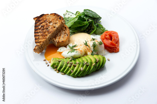 Poached egg, avocado and toast in a plate. Isolated on white.