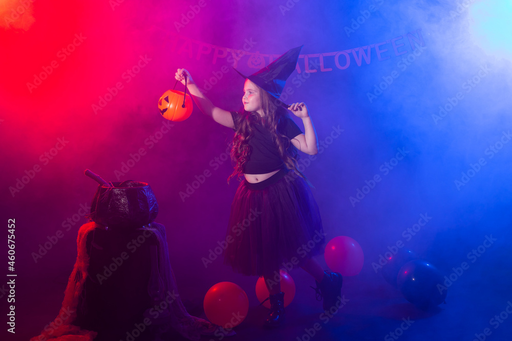 Funny child girl in witch costume for Halloween with pumpkin Jack.