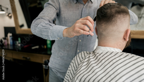 Hairdresser cutting hair of man.