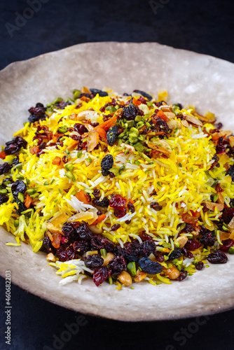 Traditional Persian tahdig jeweled javaher polow bride basmati rice with dried fruits and berries served as close-up on a rustic design plate photo