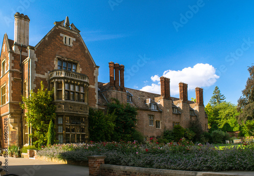 Facade of historical bricked Christ's College building with a garden and tall chimney stacks at Cambridge England photo