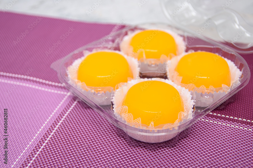 Quindins embalados em um recipiente plástico, doce tradicional na culinária brasileira, feito com gemas de ovos, açúcar e coco ralado. Quindins embalados em um recipiente plástico, doce tradicional na culinária brasileira, feito com gemas de ovos, açúcar e coco ralado.