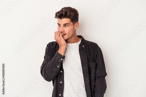 Young caucasian man isolated on white background biting fingernails, nervous and very anxious.