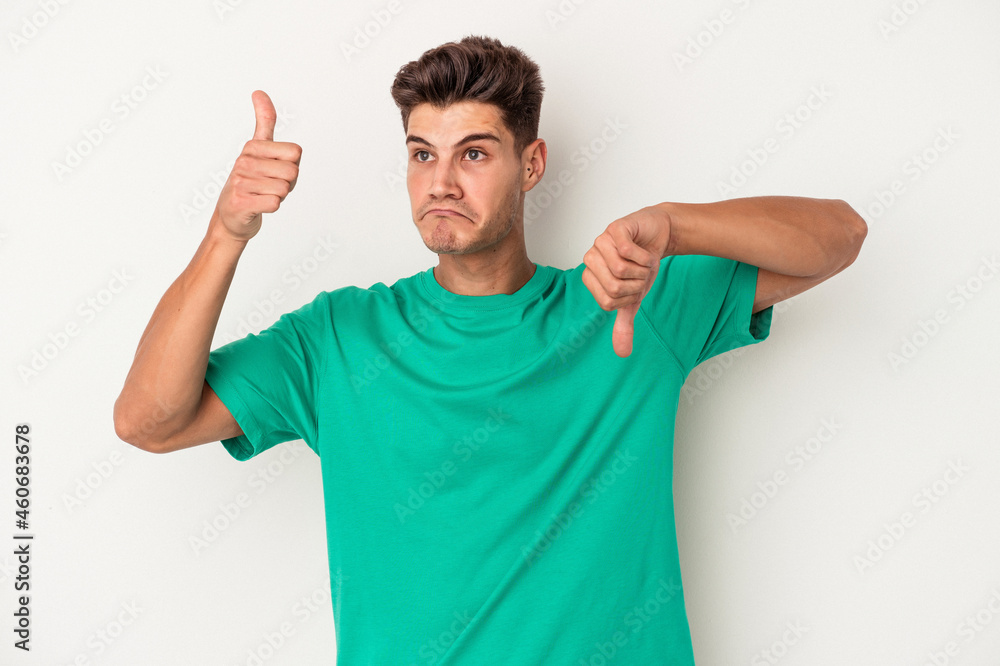 Young caucasian man isolated on white background showing thumbs up and thumbs down, difficult choose concept Young caucasian man isolated on white background showing thumbs up and thumbs down, difficult choose concept