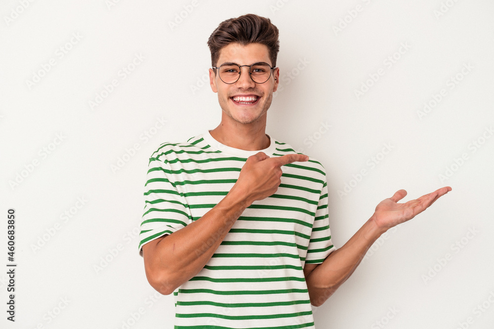 Young caucasian man isolated on white background excited holding a copy space on palm. Young caucasian man isolated on white background excited holding a copy space on palm.