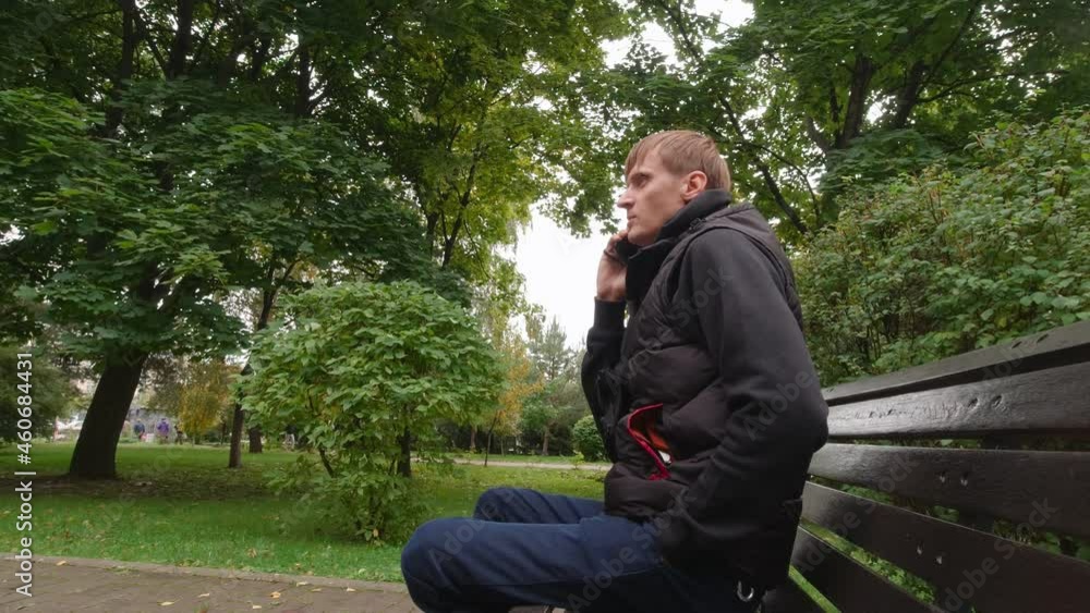 Man talking on the phone in the park side view Man talking on the phone in the park side view