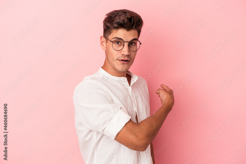 Young caucasian man isolated on pink background smiling and pointing aside, showing something at blank space. Young caucasian man isolated on pink background smiling and pointing aside, showing something at blank space.