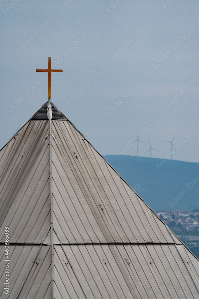 a golden cross on the roof of a pyramid like architecture church witch chills and forest in the background a golden cross on the roof of a pyramid like architecture church witch chills and forest in the background