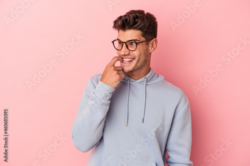Young caucasian man isolated on pink background relaxed thinking about something looking at a copy space.