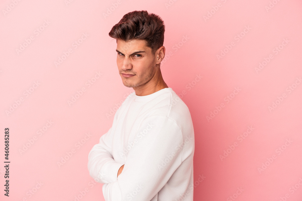 Young caucasian man isolated on pink background suspicious, uncertain, examining you. Young caucasian man isolated on pink background suspicious, uncertain, examining you.