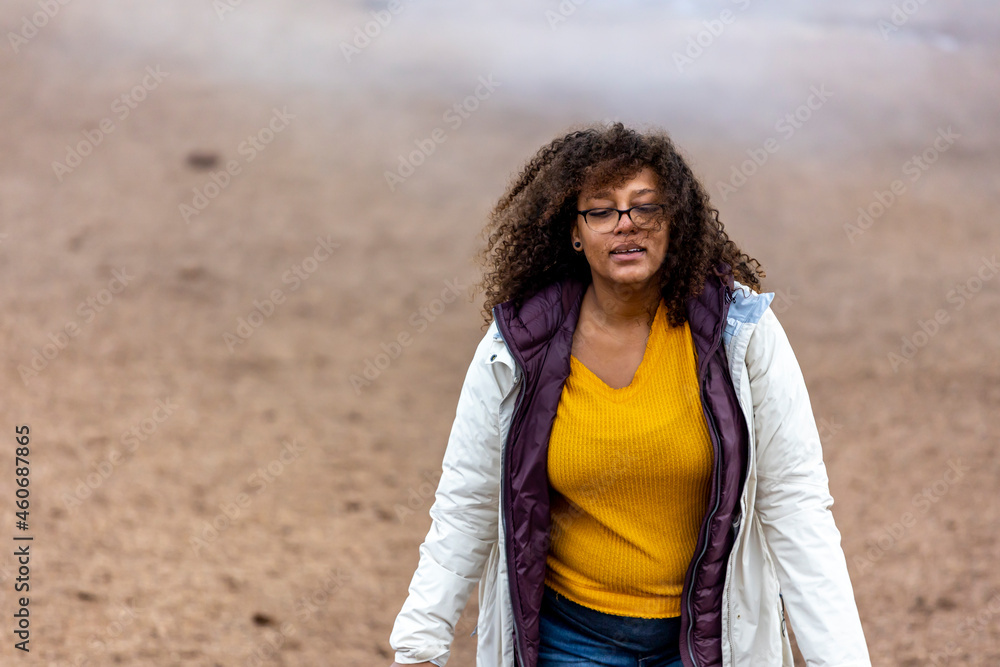  portrait of an African American mixed race woman smiling excitingly outdoors in nature. the beautiful curly hair lady is happy and positive with glasses on her face