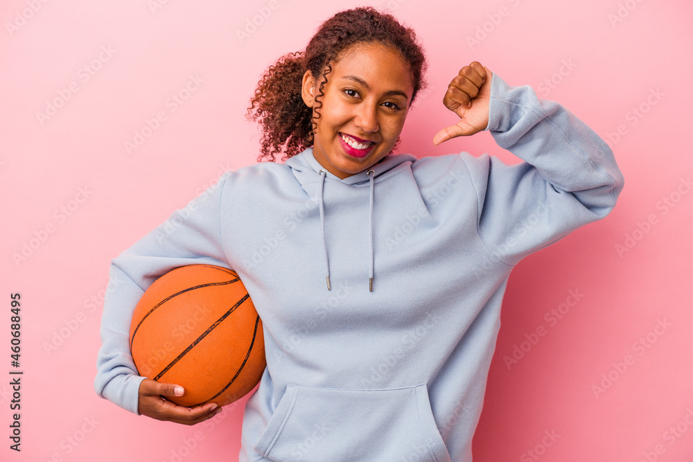 Young african american man playing basketball isolated on pink background feels proud and self confident, example to follow. Young african american man playing basketball isolated on pink background feels proud and self confident, example to follow.