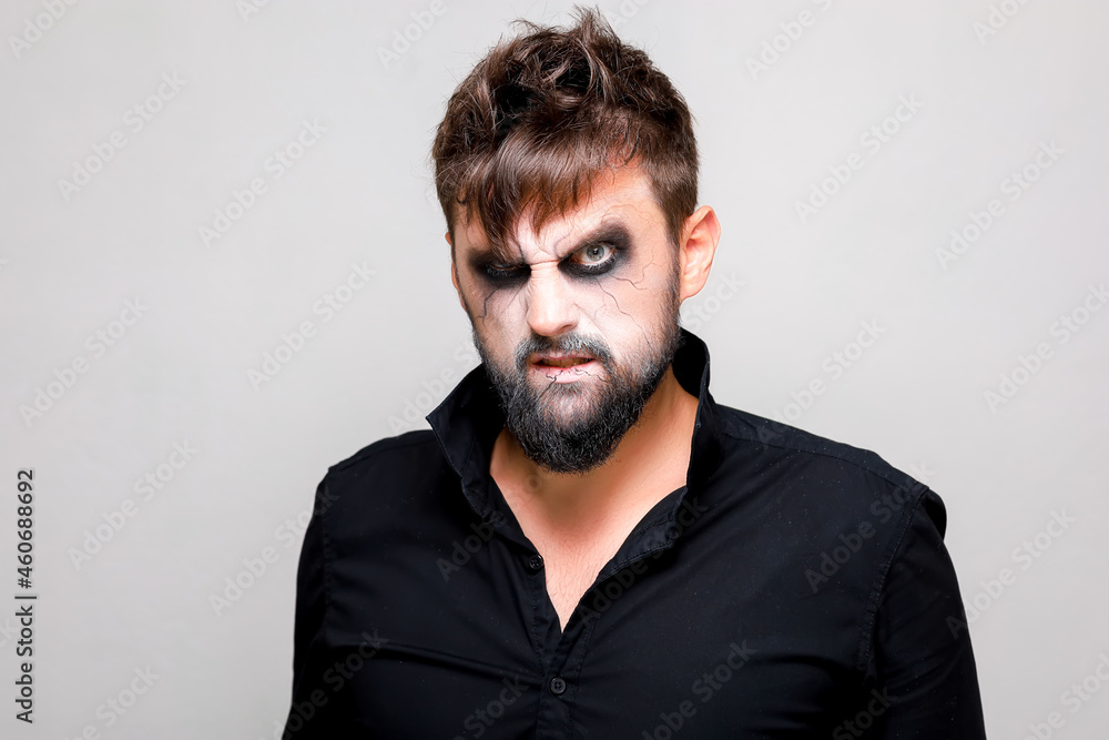 undead-style makeup on a bearded man who looks from under his brows and grimaces undead-style makeup on a bearded man who looks from under his brows and grimaces