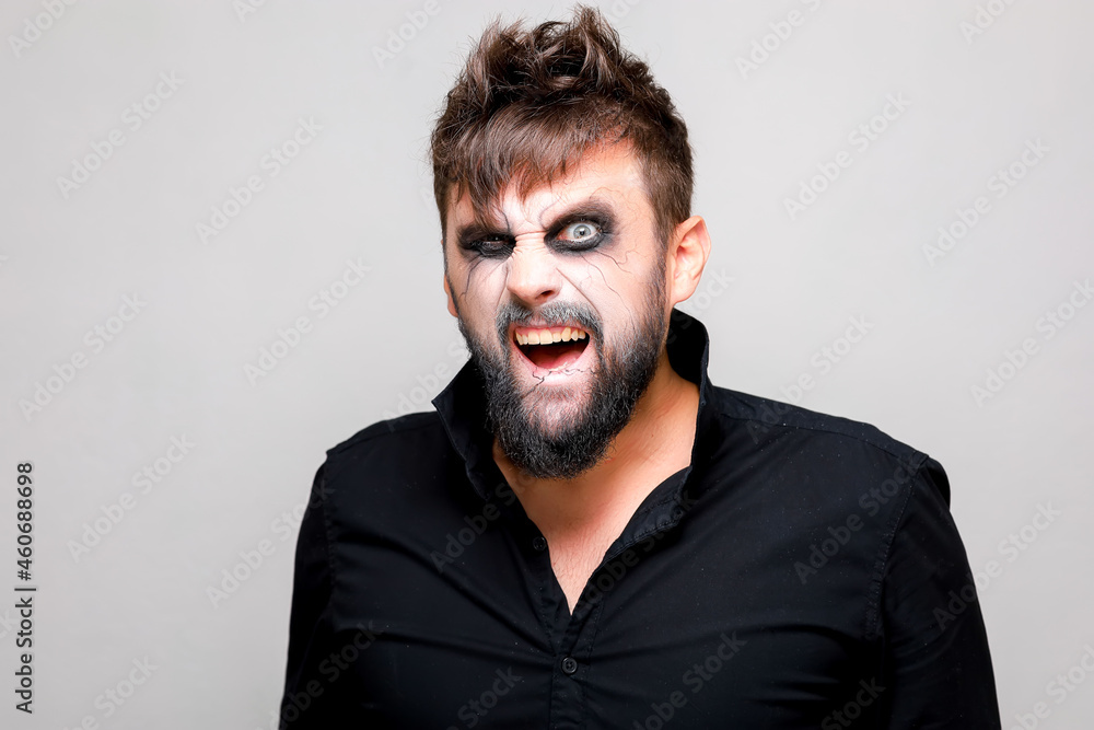 undead-style makeup on a bearded man who looks from under his brows and grimaces undead-style makeup on a bearded man who looks from under his brows and grimaces