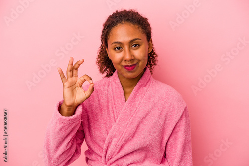 Young african american woman wearing a bathrobe isolated on pink background cheerful and confident showing ok gesture.