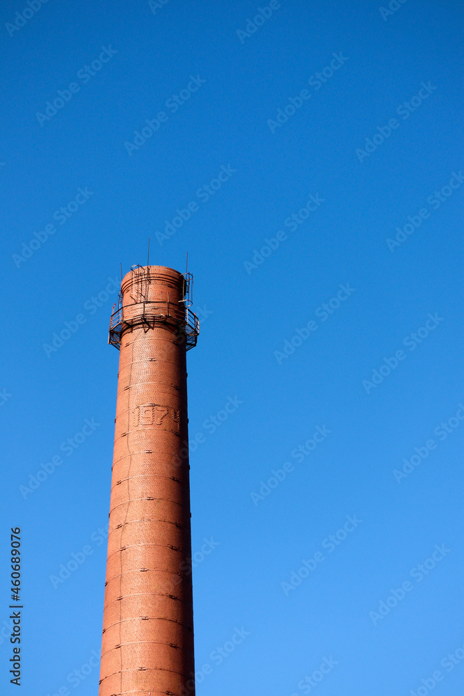 red brick old chimney of a factory on blue sky background