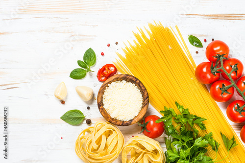 Pasta ingredients background. Pasta, fresh tomatoes, parmesan, herbs and spices at white wooden table. Top view with copy space.