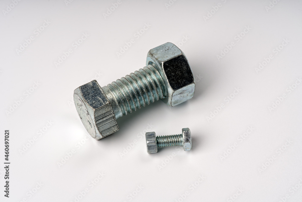 The largest and smallest bolts with nuts on a white background. The largest and smallest bolts with nuts on a white background.