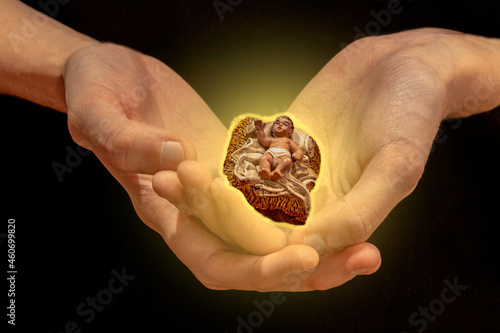 hand of a child holding the figure of the baby jesus from the figure of a christian nativity scene