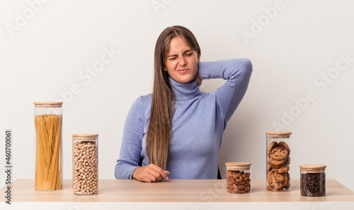 Young caucasian woman sitting at a table with food pot isolated on white background suffering neck pain due to sedentary lifestyle.
