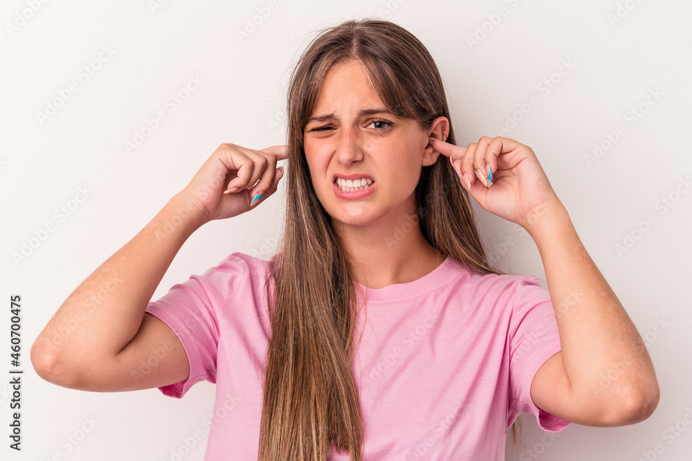Young caucasian woman isolated on white background covering ears with fingers, stressed and desperate by a loudly ambient. Young caucasian woman isolated on white background covering ears with fingers, stressed and desperate by a loudly ambient.