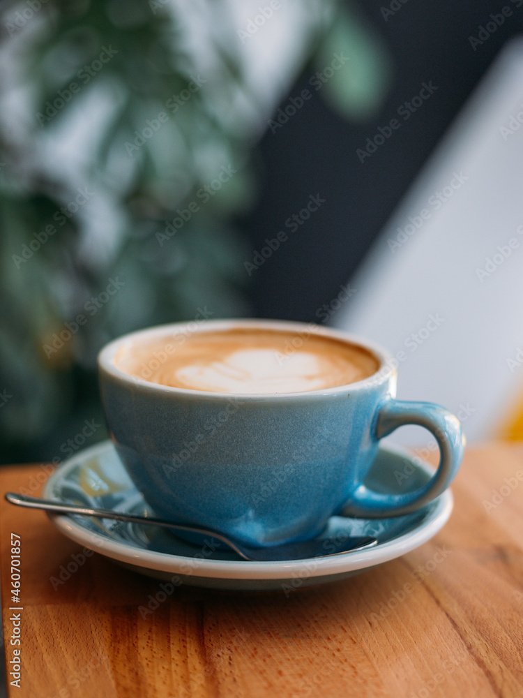 One Cup of cappuccino with latte art. Coffee in blue cup on wooden table in cafe. Concept of easy breakfast. One Cup of cappuccino with latte art. Coffee in blue cup on wooden table in cafe. Concept of easy breakfast.