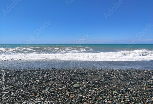 Black sea background with stone beach and waves.