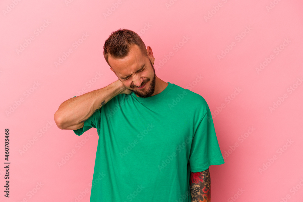 Young caucasian man with tattoos isolated on pink background having a neck pain due to stress, massaging and touching it with hand. Young caucasian man with tattoos isolated on pink background having a neck pain due to stress, massaging and touching it with hand.
