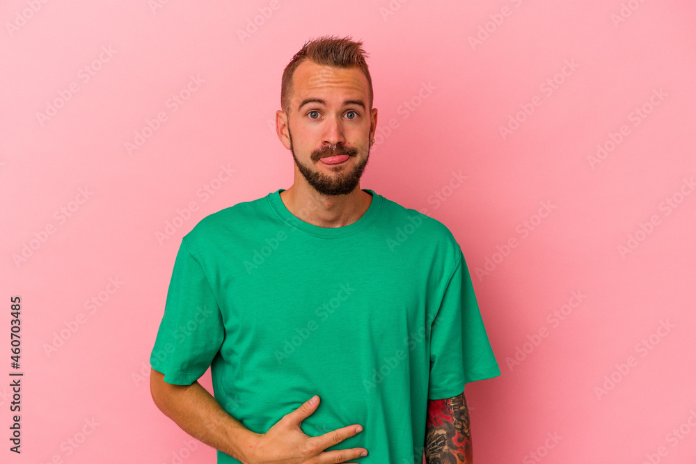 Young caucasian man with tattoos isolated on pink background touches tummy, smiles gently, eating and satisfaction concept. Young caucasian man with tattoos isolated on pink background touches tummy, smiles gently, eating and satisfaction concept.