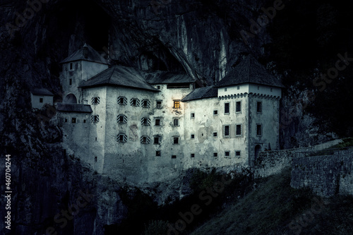 haunted mystic eerie predjama castle built into a mountain in the nature with light from one window photo