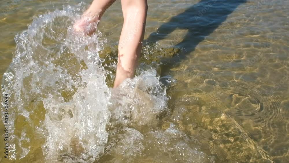 Close up view on playful kid legs running on wet sand in shallow water at the beach feeling positive emotion. Full HD slow motion video. Summer holidays concept. Close up view on playful kid legs running on wet sand in shallow water at the beach feeling positive emotion. Full HD slow motion video. Summer holidays concept.