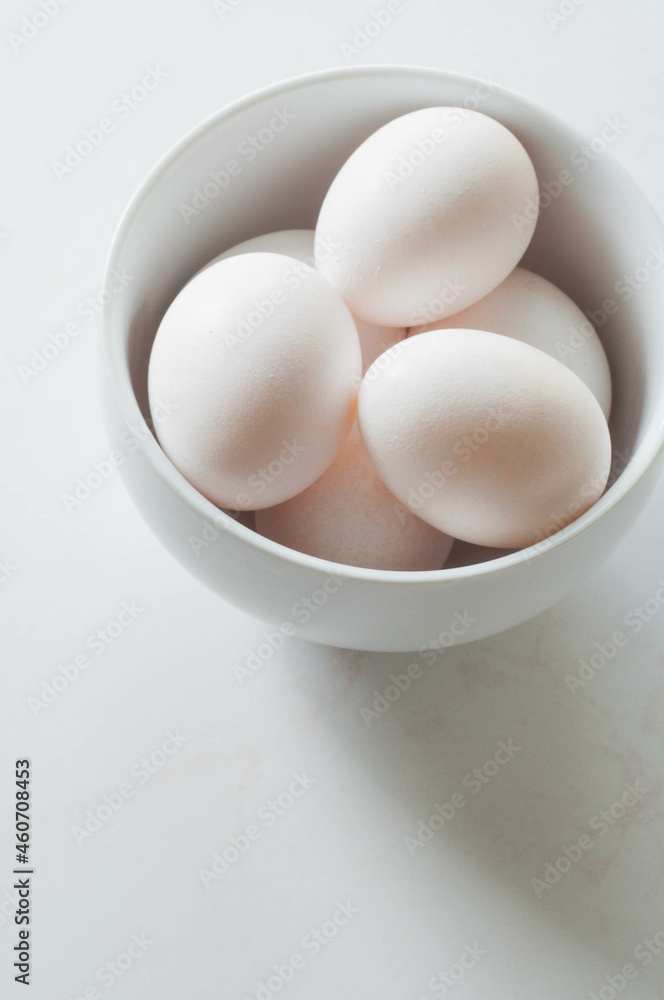 White eggs in a white bowl on a white background. White eggs in a white bowl on a white background.