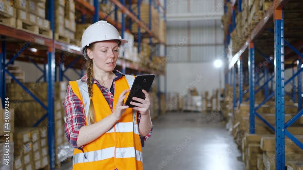 Warehouse worker working process checking the package using a tablet in a large warehouse distribution center. Caucasian female inspects cargo inventory.